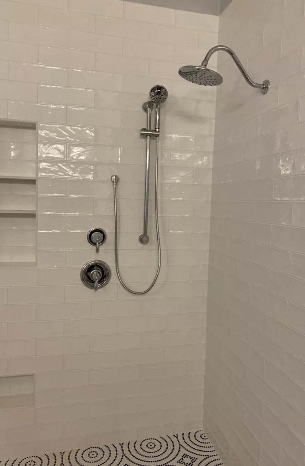 Chrome shower trim with rainfall head, hand shower, and slide bar on white subway tile