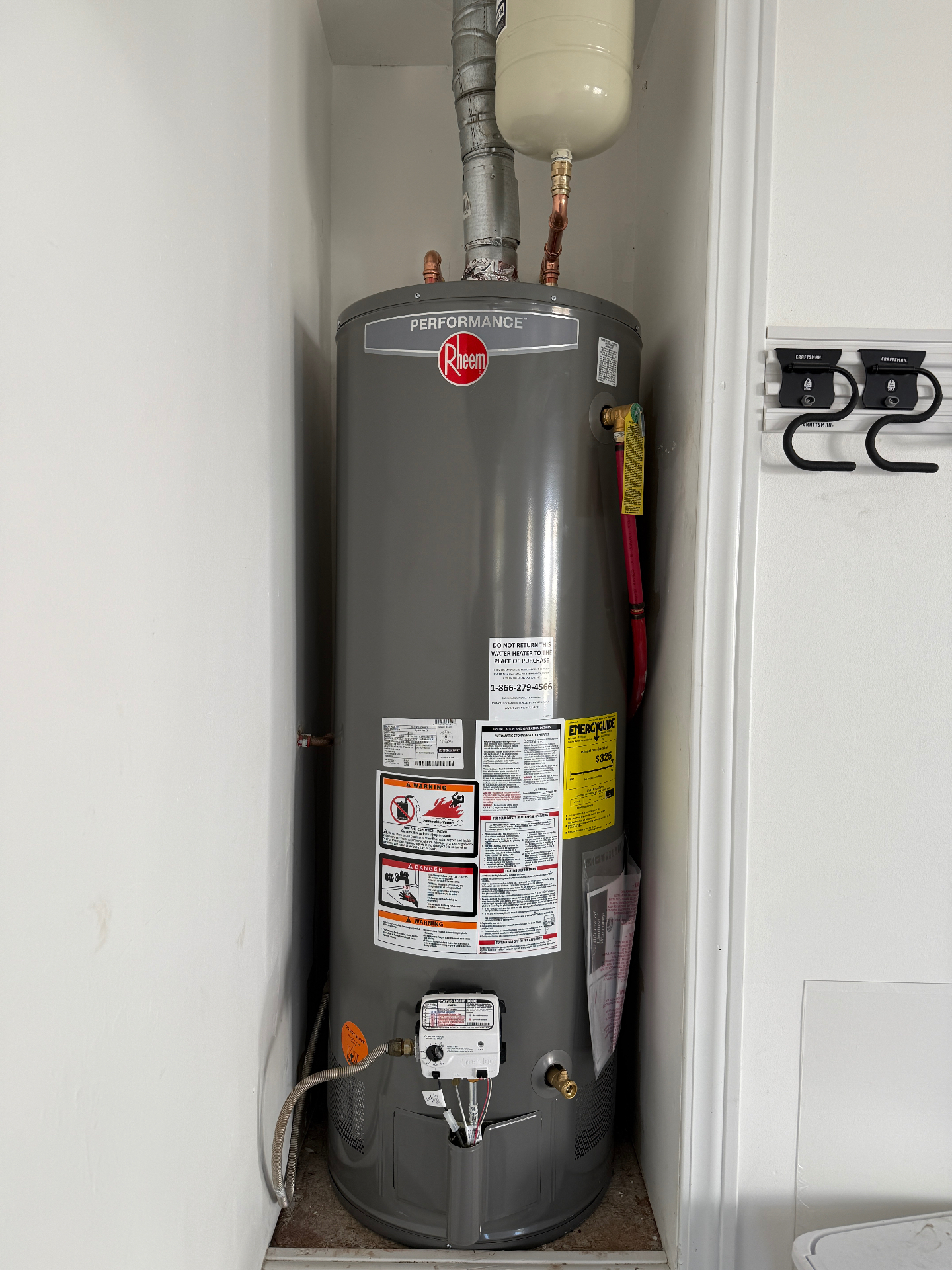 Installed Rheem water heater in a narrow closet with expansion tank above